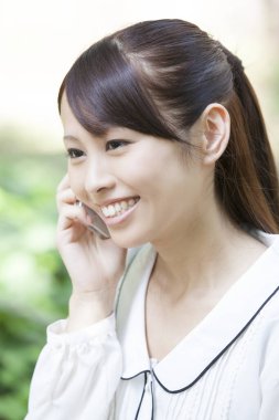 Güzel Asyalı kadın akıllı telefondan konuşuyor.