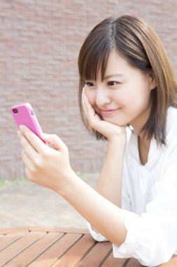 Genç Japon kadın dışarıda akıllı telefon kullanıyor.