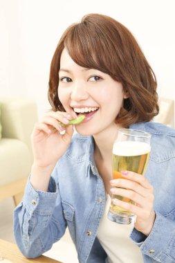 Neşeli Japon kadın evde bira içiyor.