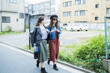 İki genç kız arkadaş şehir sokaklarında yürüyor.