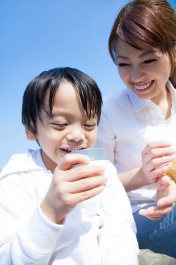 Neşeli Asyalı anne ve oğlu parkta piknik yapıyor.
