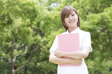 Parkta klasörü olan Asyalı bir üniversite öğrencisi.