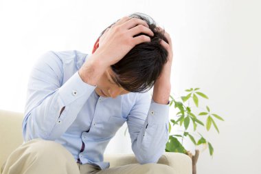 Baş ağrısı olan genç adam. Koltukta oturuyor. 