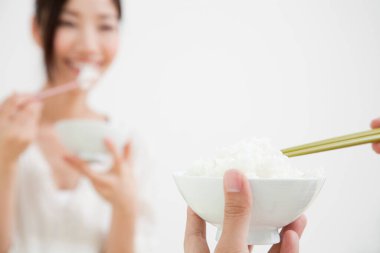 Asyalı kadın ve erkek birlikte yemek yiyorlar.