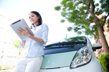 Tablet bilgisayarı olan kadın arabanın yanında bekliyor.