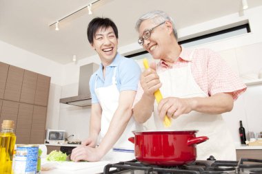 Mutlu baba ve oğul ev mutfağında birlikte yemek pişiriyor.