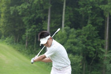 Genç Japon adam gündüz golf oynuyor. 