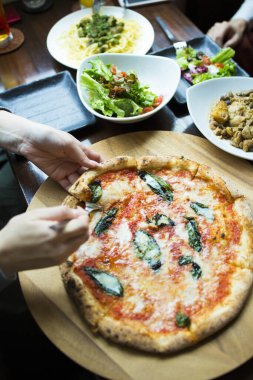 Bir kadın restoranda peynirli bir dilim lezzetli pizza yiyor, yakın çekim manzaralı. 