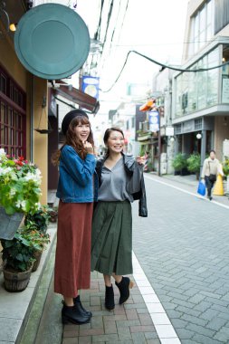 Genç, güzel Asyalı kadınlar sokakta yürüyor.