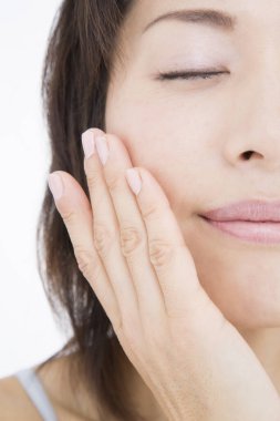 Genç Asyalı kadın yüzüne dokunuyor. 