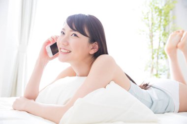 Yatakta akıllı telefon kullanan kadın. 