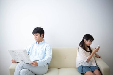 Baba gazete okuyor ve kızı akıllı telefon kullanıyor. 