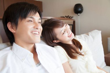 Oturma odasındaki koltukta oturan Asyalı çift.