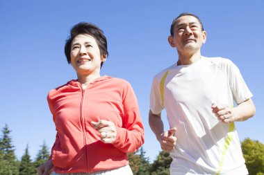 Yaşlı çift güneşli bir günde parkta koşuyor.