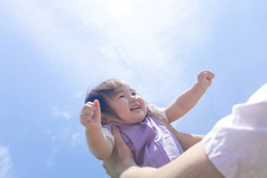 Asyalı bebek babasıyla oyun parkında oynuyor.