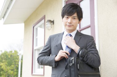 Asyalı işadamı binanın önünde duruyor.