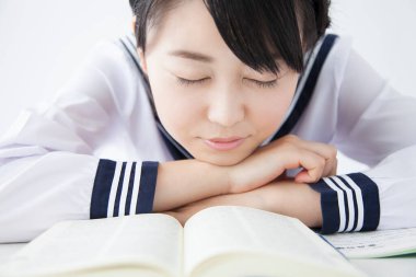 Asyalı genç öğrenci kitapların üzerinde uyuyor. 