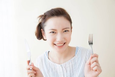 Çatal ve bıçaklı genç Asyalı kadın.