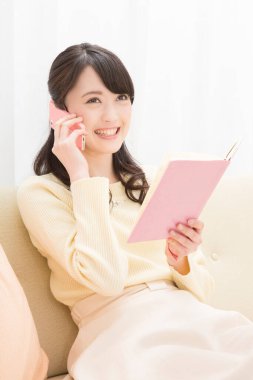 Akıllı telefondan konuşan gülümseyen Asyalı kadın. Toplantı programına bakıyorum. randevu alınıyor