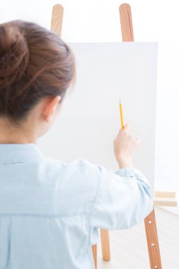 Odada tuvale resim çizen genç bir kadın 