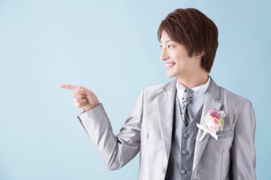 Asyalı genç damat mavi arkaplanı fotokopi aletiyle işaret ediyor