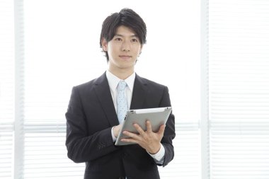 Ofisinde tableti olan genç Asyalı bir iş adamı. 