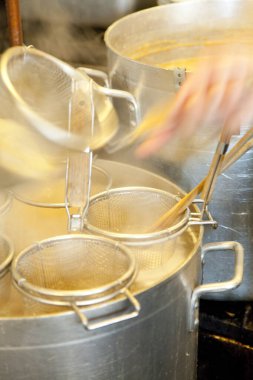 Mutfakta metal süzgeçli buharlı tencereler.