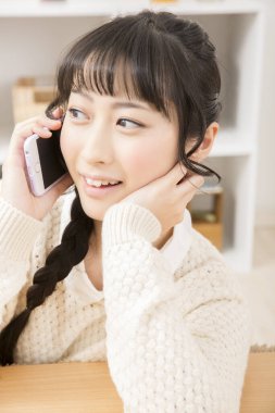 Güzel Asyalı genç bir kadın telefonda konuşuyor.