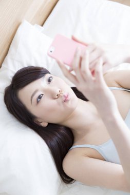 Genç bir kadın evde akıllı telefon kullanıyor.