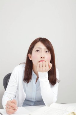 Ofisteki masada düşünen genç bir kadın.