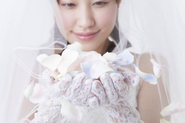 portrait of beautiful young bride holding flower petals