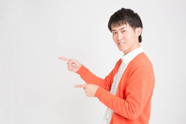 Asyalı genç adam işaret ediyor, stüdyo çekimi.