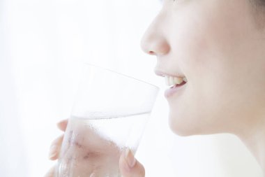 Asyalı genç bir kadının sabahları camdan su içmesi.