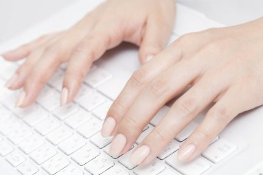 Kadın elleri beyaz klavyede, yakın plan.