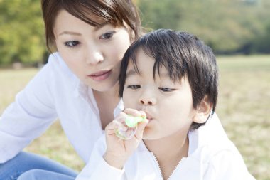Asyalı anne ve oğlu baloncuk üflüyor. 