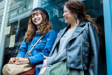 İki bayan arkadaş dükkanda yan yana dururken gülümsüyor.