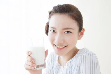 Genç Asyalı kadın süt içiyor