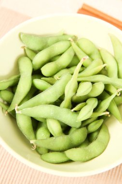 Beyaz kaseyi dolduran taze yeşil edamame kapsülleri