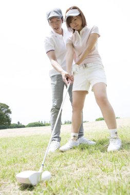 Genç bayan arkadaşlar sahada golf oynuyorlar.