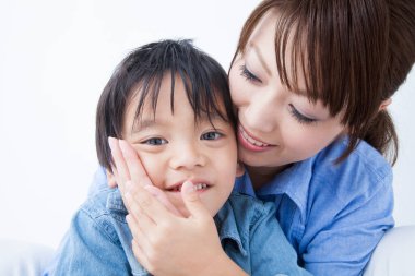 Stüdyoda poz veren Asyalı genç anne ve tatlı oğlunun portresi.