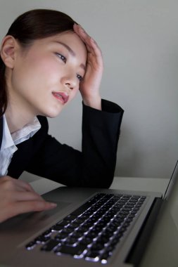 Dizüstü bilgisayar kullanan genç bir iş kadını. 