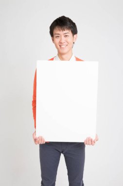 Gri arka planda boş ilan panosu tutan genç bir adamın portresi.