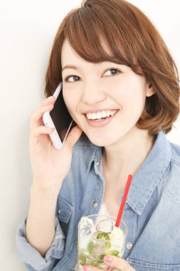 Elinde içki tutan ve telefonla konuşan güzel bir Japon kadının portresi.