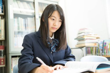 Kütüphanedeki güzel Japon kız öğrencinin açık hava portresi, bulanık arka plan 