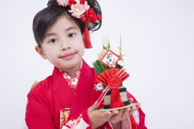 Beyaz stüdyo arka planında geleneksel kırmızı kimono giyen güzel Japon kızın portresi.