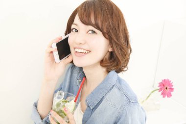 Elinde cam tutan ve telefonla konuşan güzel Japon kadının portresi.