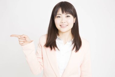Pembe ceketli genç Japon kadının beyaz arka planda parmak göstererek stüdyo portresi. 