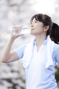 Kapatın güzel, olgun Asyalı kadın su içiyor.