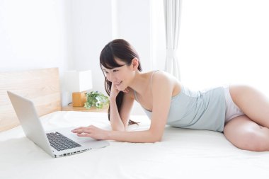 Genç Asyalı kadın evde dizüstü bilgisayarla çalışıyor.