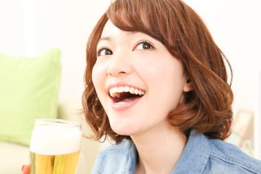 Neşeli Japon kadın evde bira içiyor.